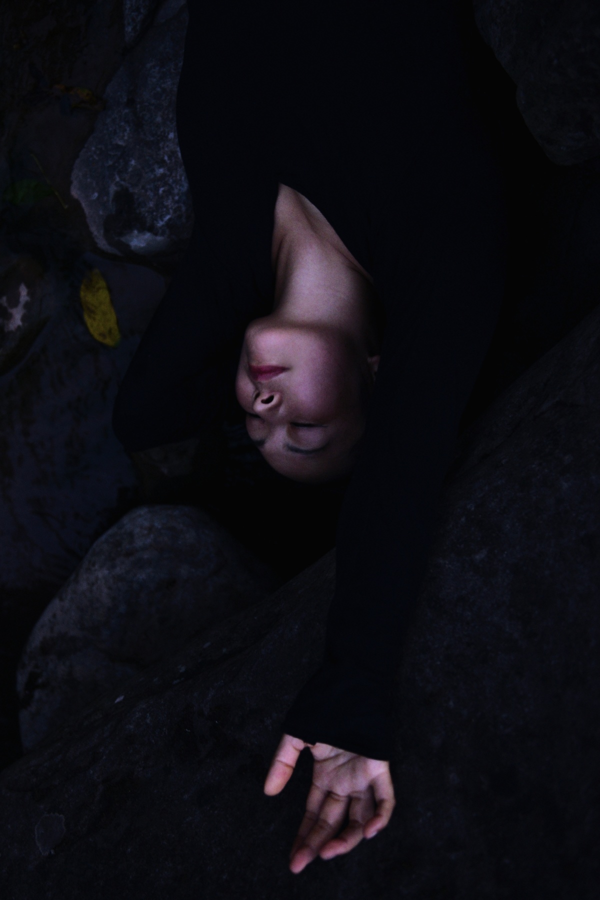一个人在黑暗中 双手捂住脸 眼睛盯着岩石。