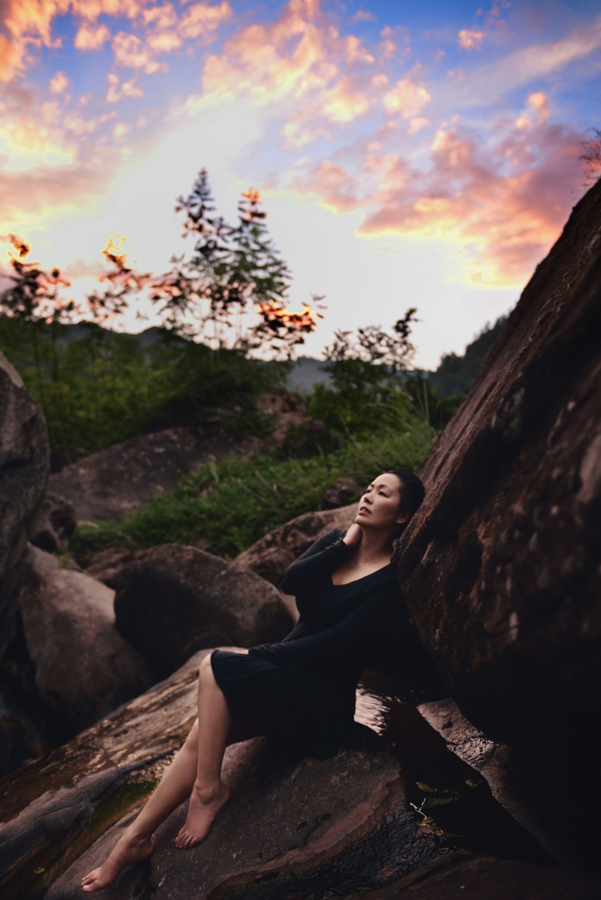 一个年轻女子坐在夕阳下的大型岩石上