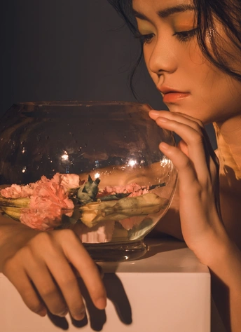 一个年轻女子拿着一碗花在水中