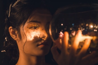 一幅年轻女子的画像 她手里拿着一个酒杯 面前放着点燃的蜡烛 手里拿着泡沫