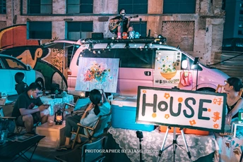 人们坐在活动现场 车侧有标志