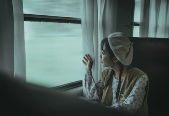 一个年轻女子独自坐在火车上 望着窗外。