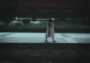 一个穿着连衣裙的女人站在一个黑暗的夜晚在伞下