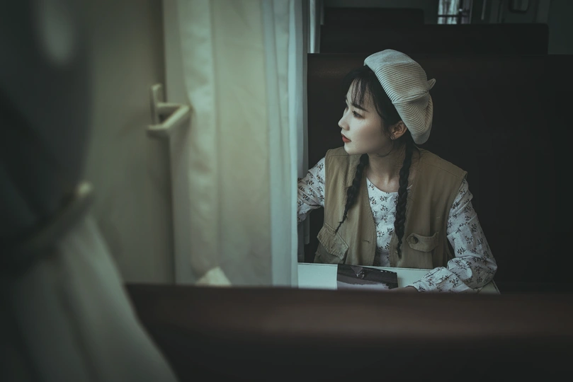 一位年轻女子坐在桌子旁 对着镜子看。