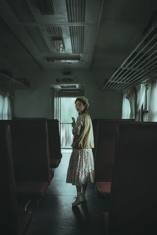 一个年轻女子站在一辆黑暗的火车车厢里 透过窗户向外看。