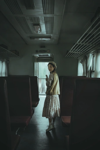 一个年轻女子站在一辆黑暗的火车车厢里 透过窗户向外看。
