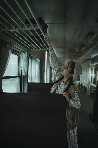 一位年轻女子身着制服 正在火车窗口向外看。