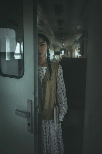 一位年轻女子站在一列火车的走廊里