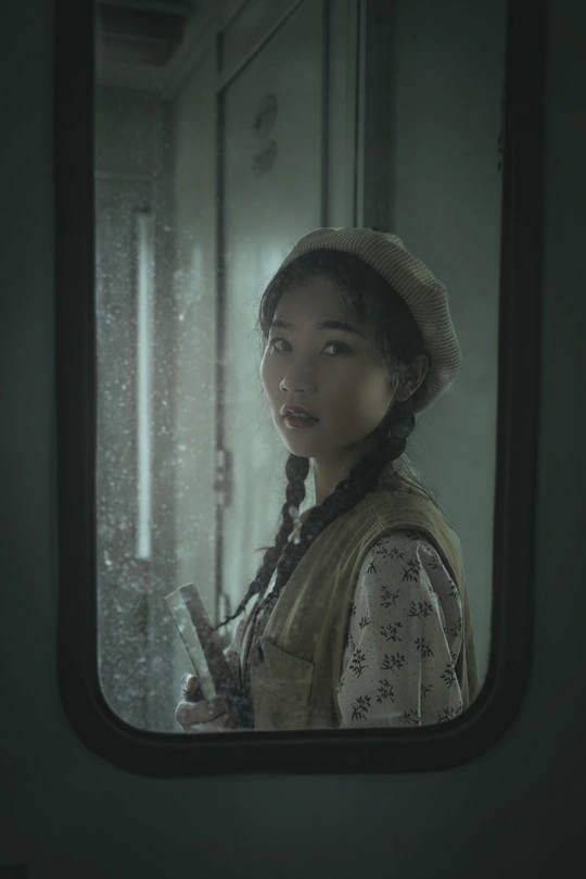 一位戴帽子的年轻女子正在火车窗口向外看 而另一个女孩站在外面。