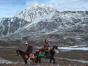 一些人在马背上穿越一个雪地田野 前方是山脉。