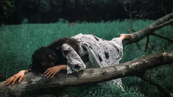 一位年轻女子躺在森林中的一片树枝上