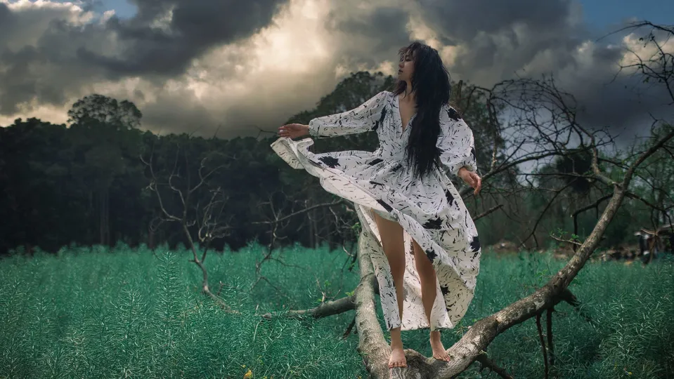 一位穿着白色连衣裙站在绿色原野上的女人