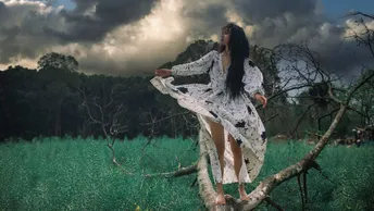 一位穿着白色连衣裙站在绿色原野上的女人