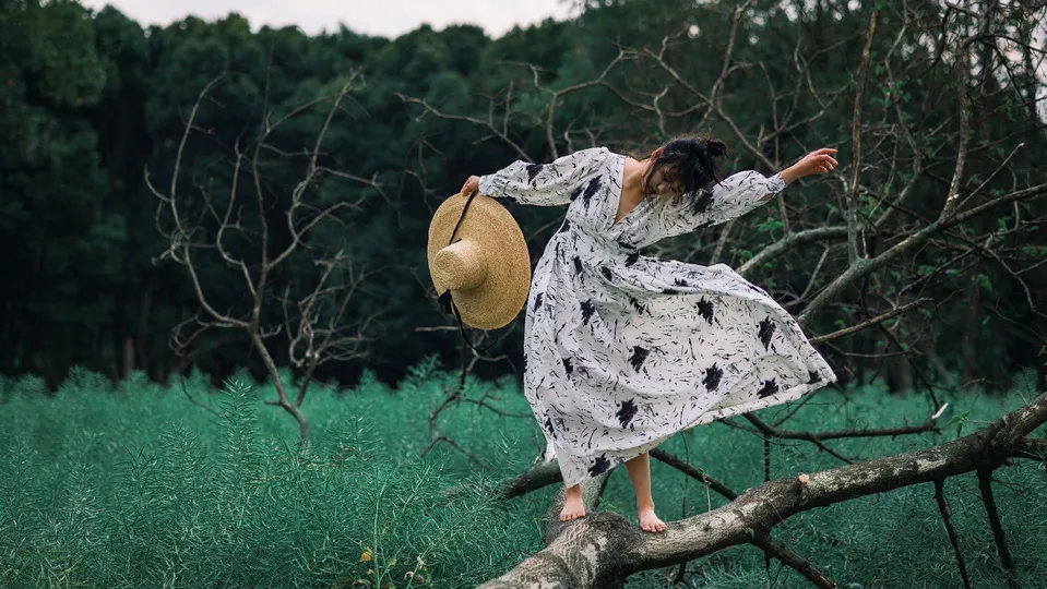 一位戴帽子的女士站在一棵树的树枝上