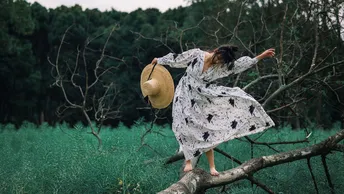 一位戴帽子的女士站在一棵树的树枝上