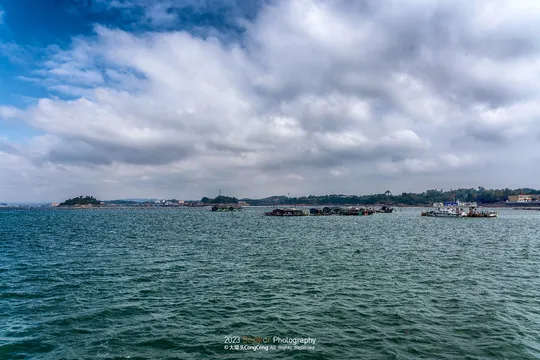 海洋中有一大片水域 远处有艘船和一座城市 在云天之间。