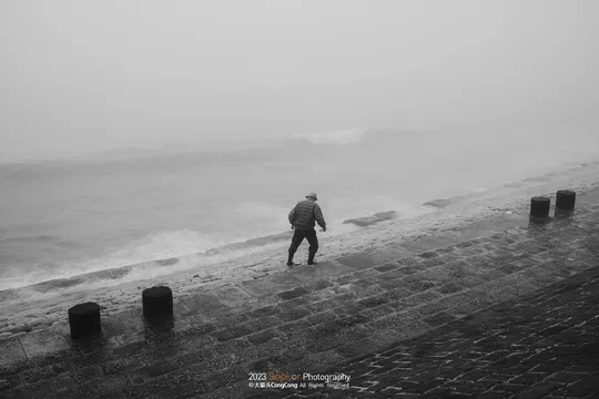 一个人在雾中的海滩上行走 背景是海洋。