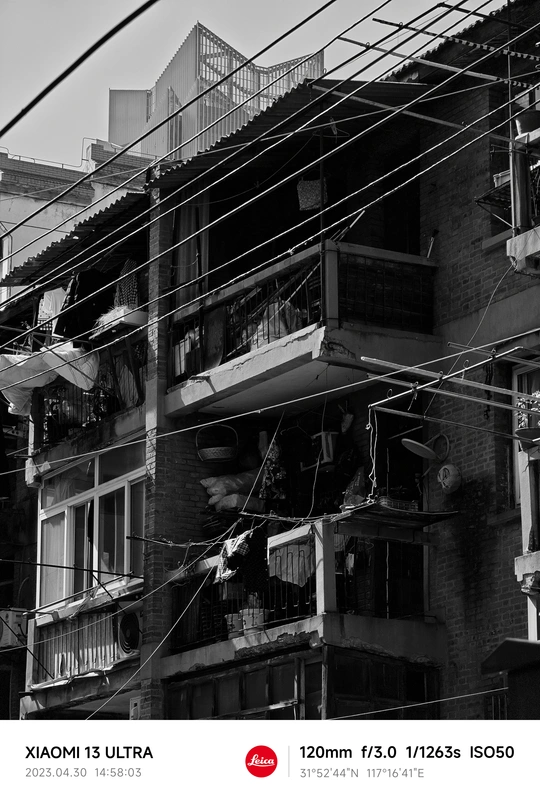 旧建筑的黑白照片 上方有电线杆在窗户上方。