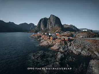 一个位于水域中央的岩石小岛 岛上建有小屋 背景是高大的山脉。