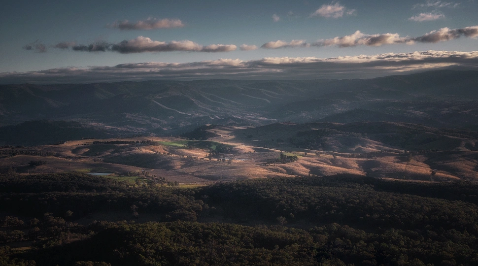 天空下低沉的太阳 山丘、森林和山脉的景观