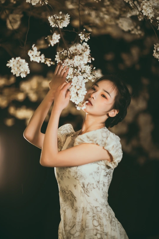 一位穿着白色连衣裙的美女手里拿着花