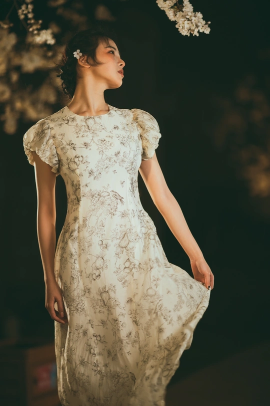 一位穿着白色连衣裙 背景中有花和树的模特