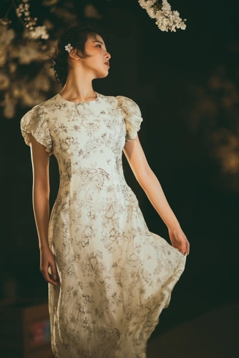 一位穿着白色连衣裙 背景中有花和树的模特