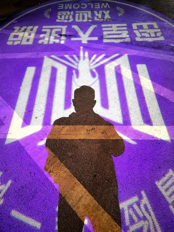 站在人行道旁边的一个紫色标志旁边的一个男人