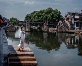 一个穿着和服的年轻女子站在运河水面上的桥上