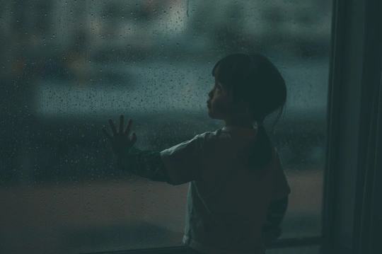 一个小女孩在雨中看窗户外
