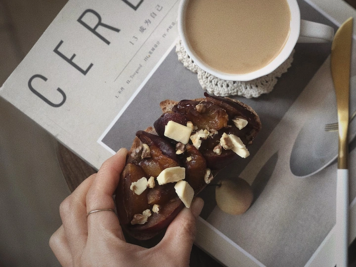 一个人在桌子上拿着一个装有坚果和巧克力的甜甜圈和一杯咖啡