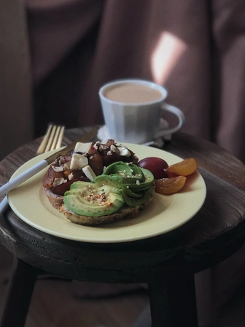 桌子上放着一小盘鳄梨、奶酪和水果 旁边是一杯咖啡
