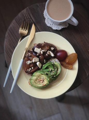 一个装有水果和蔬菜的白色盘子 放在一张木桌上 旁边放着一杯咖啡和叉子