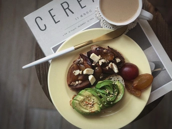 桌子上放着一盘食物 旁边是一杯咖啡和一些水果和蔬菜