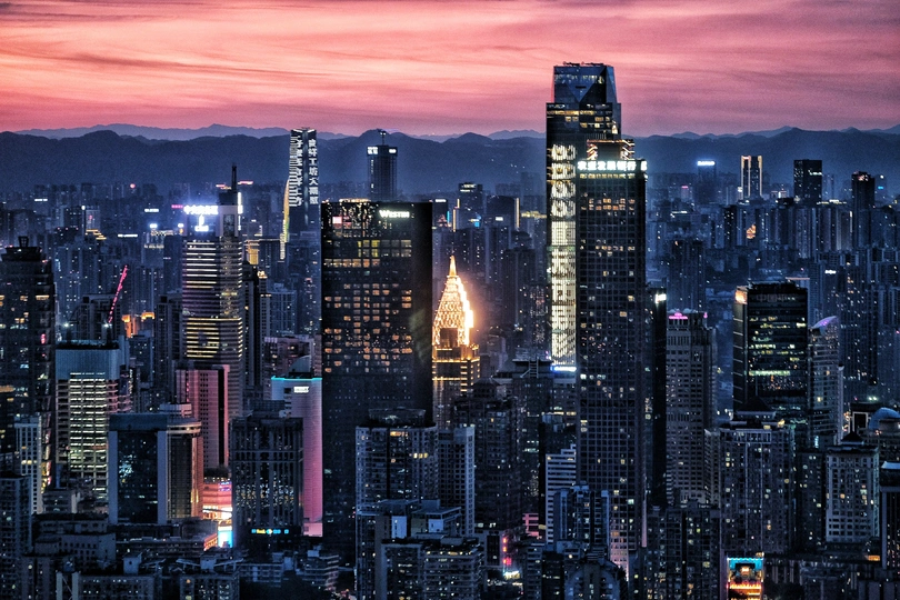 一张在日落时分拍摄的城市夜晚的照片 前景是香港和其他摩天大楼的天际线