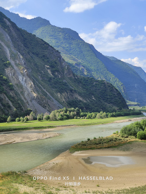 一条河流流经一个以山脉为背景的绿色山谷
