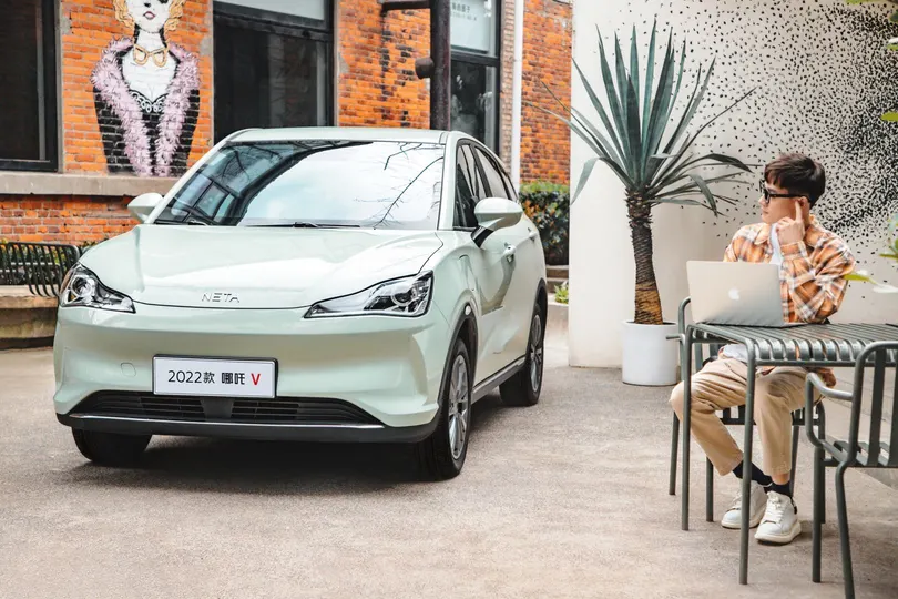 一个坐在小桌子前 电脑放在汽车外 在咖啡馆外的男人