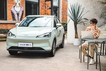 一个坐在小桌子前 电脑放在汽车外 在咖啡馆外的男人