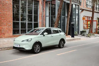 路边停着一辆小汽车 前面有一座砖楼。