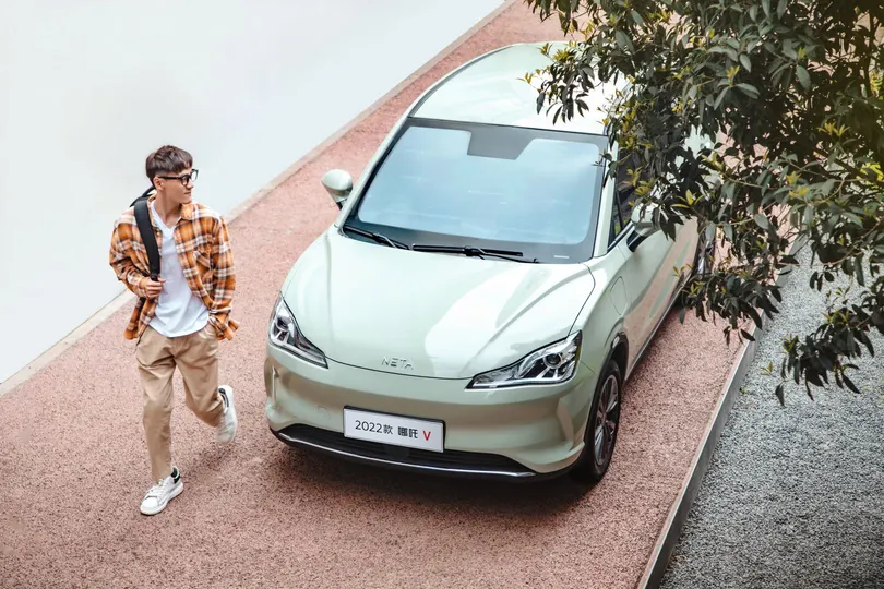 一名年轻男子走在路边停着一辆车的旁边