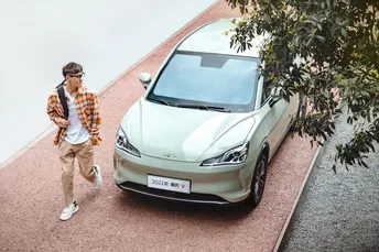 一名年轻男子走在路边停着一辆车的旁边