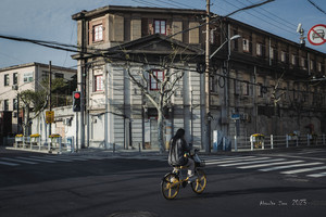 一位女士骑着黄色的自行车穿过一个路口 位于一座老建筑前。