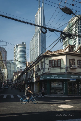 一条街道 高楼林立 一个人骑着蓝色的自行车。