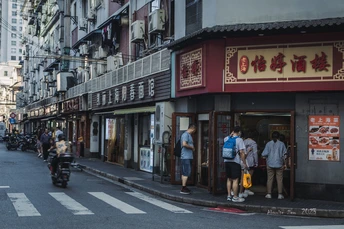 人们骑摩托车穿过一条建筑群排列的街道