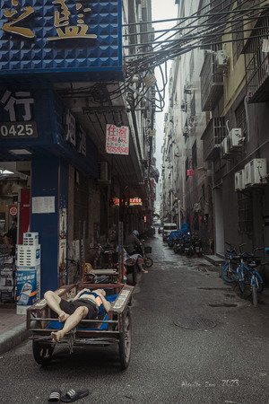 一条狭窄的巷子 建筑物之间 一个人躺在街上的手推车上。