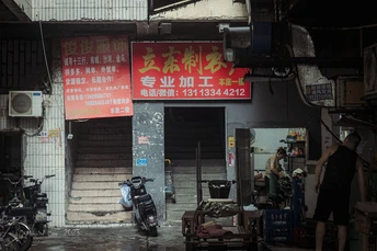 站在商店前 商店前有一辆摩托车停着的男人