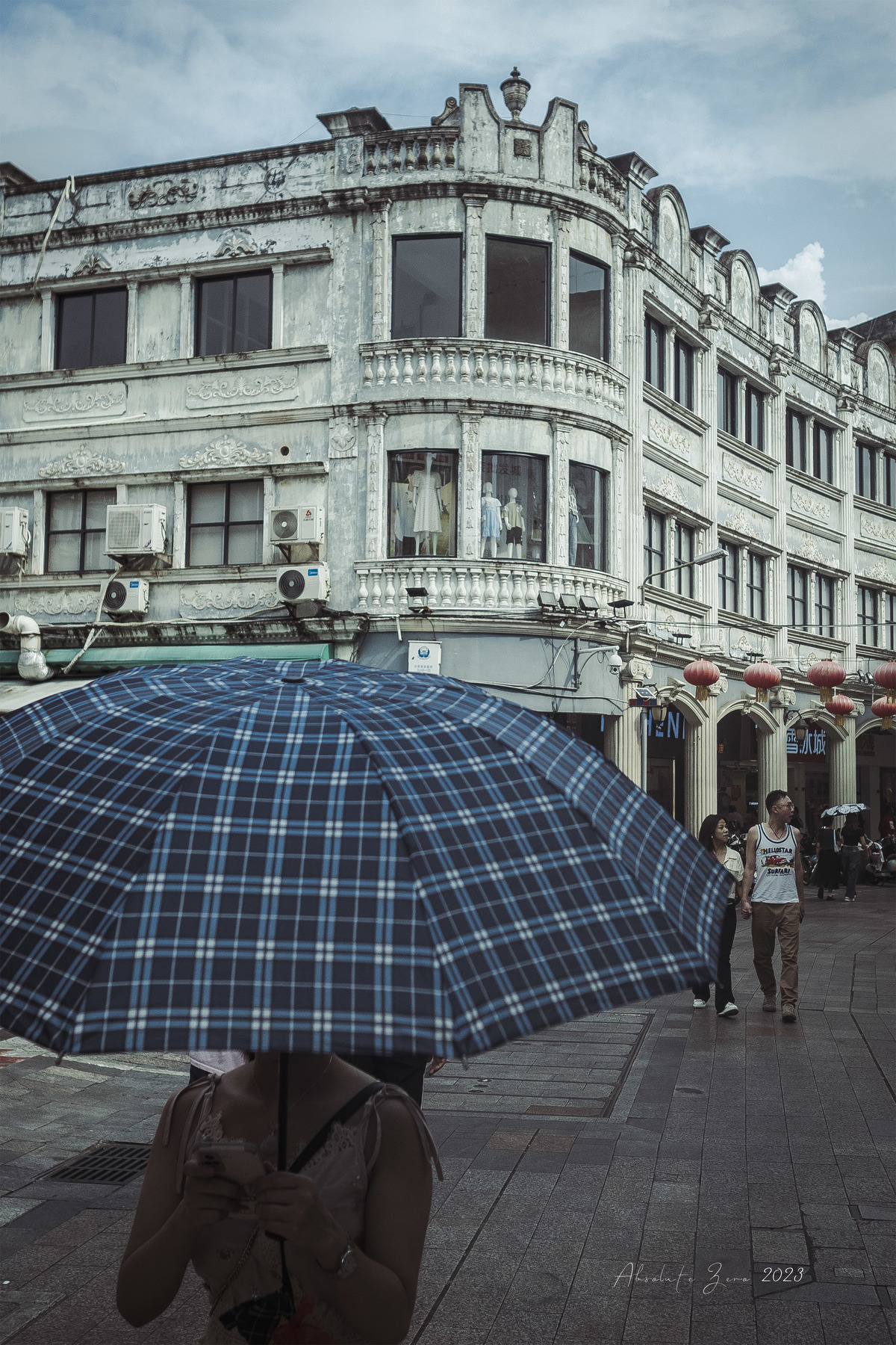 一个人站在街道上 前方是一座大楼 他手中拿着一把打开的雨伞。