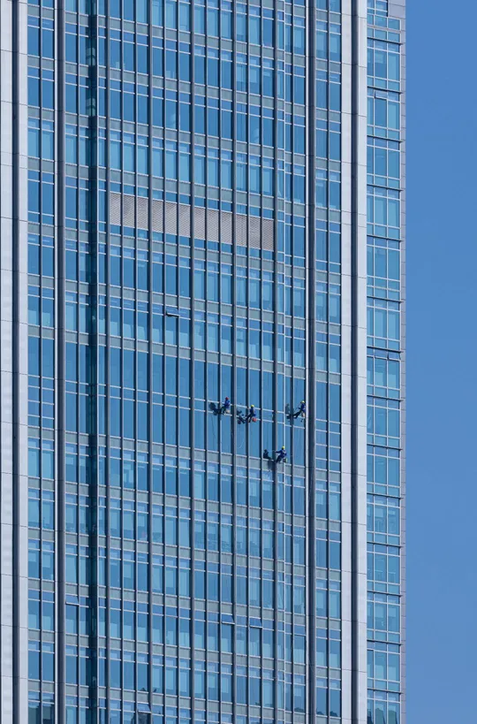 一座高大的摩天大楼 窗户是蓝色的 一架大型飞机在天空中飞行。