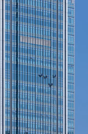 一座高大的摩天大楼 窗户是蓝色的 一架大型飞机在天空中飞行。