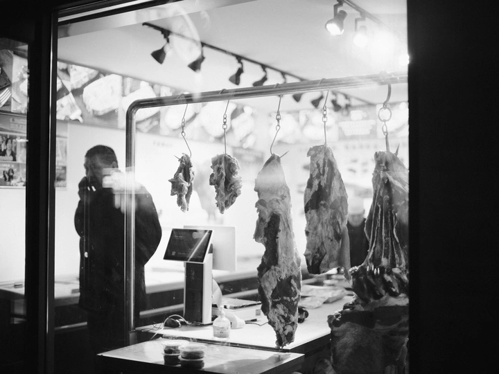 一张黑白照片 餐厅里一个人站在窗户前 桌子上堆满了肉。